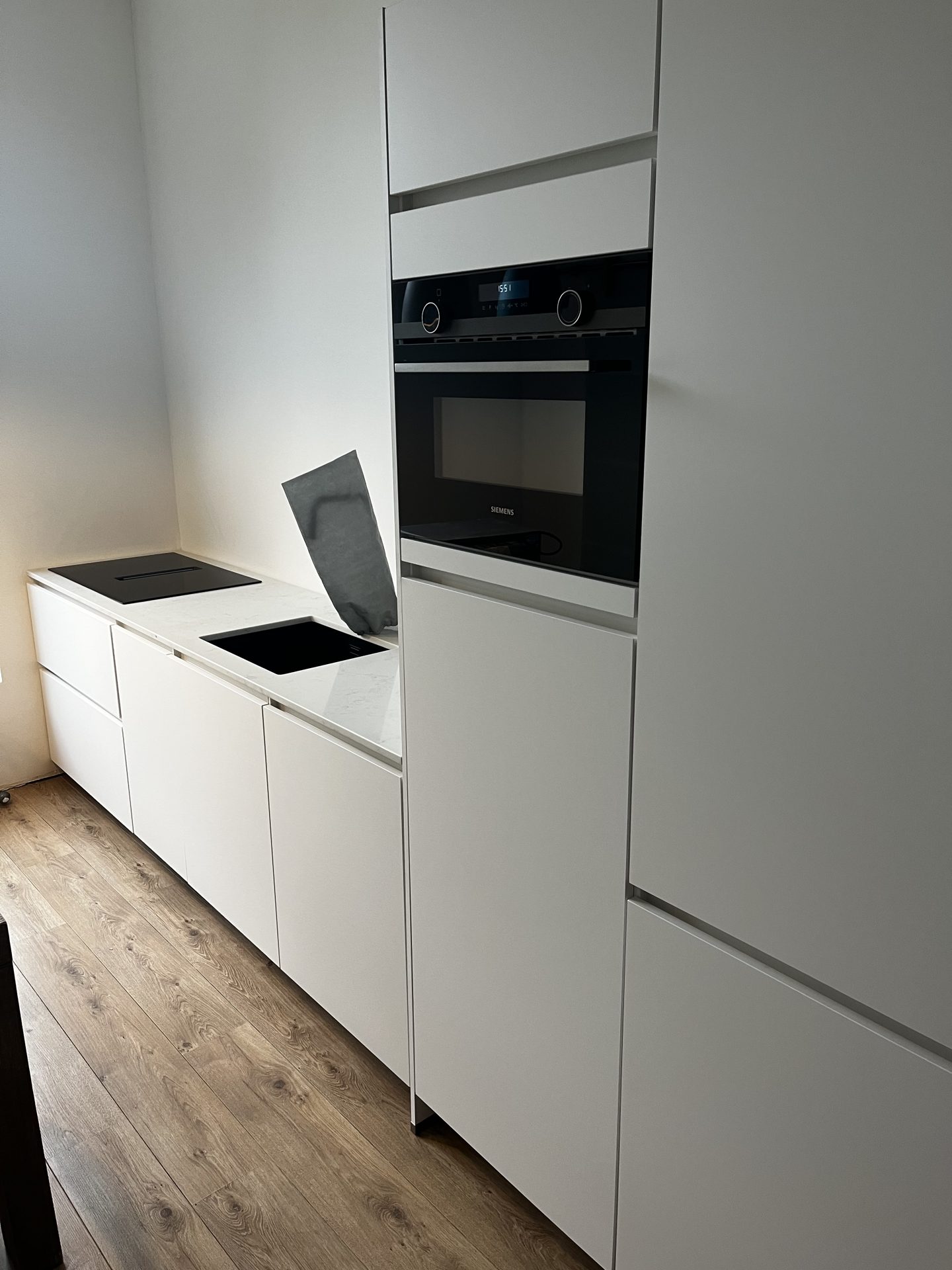 Nieuw geplaatste witte keuken met inbouwoven en kookplaat